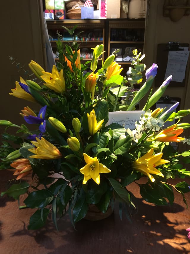 Sympathy arrangement of yellow lilies, iris, and mixed garden flowers