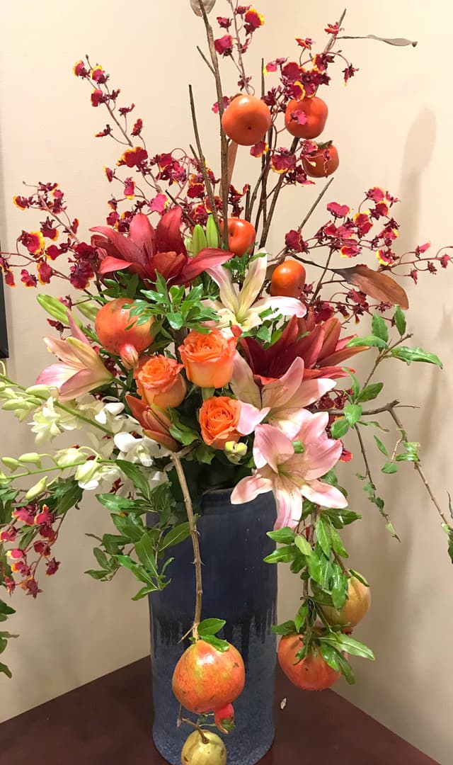 Fall arrangement of orange lilies and berries with pomegranate accents