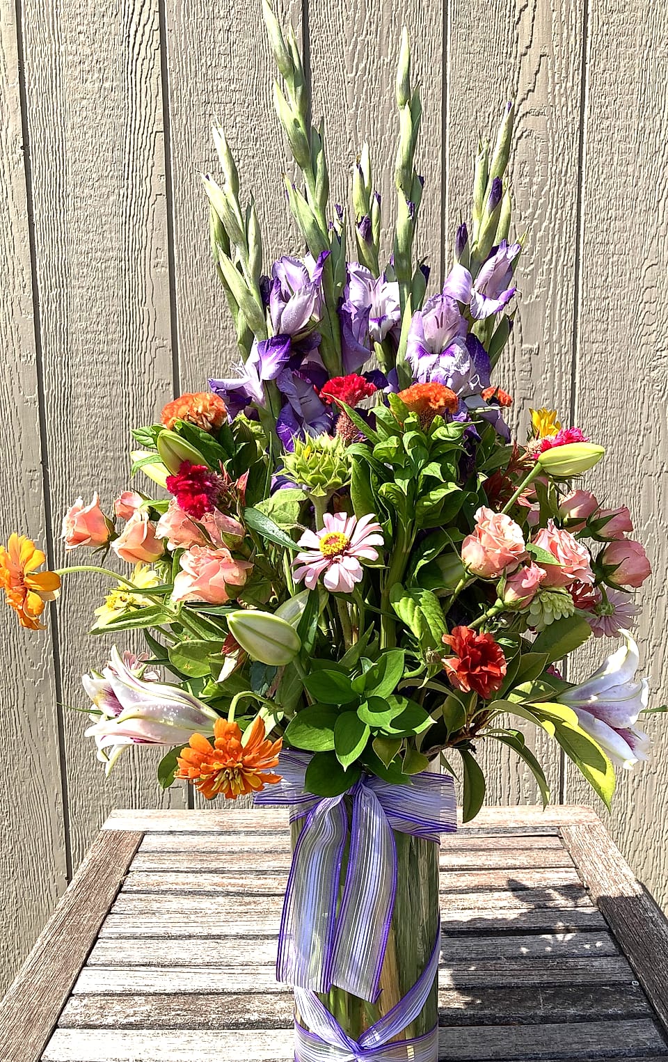 English garden arrangement of purple gladiolus, lisianthus, and orange spray roses