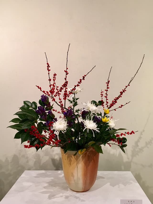 Junten-ryū ikebana of red berries, white chrysanthemums, and dark foliage