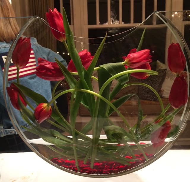 Red tulips curled inside a glass bubble bowl with an American flag accent
