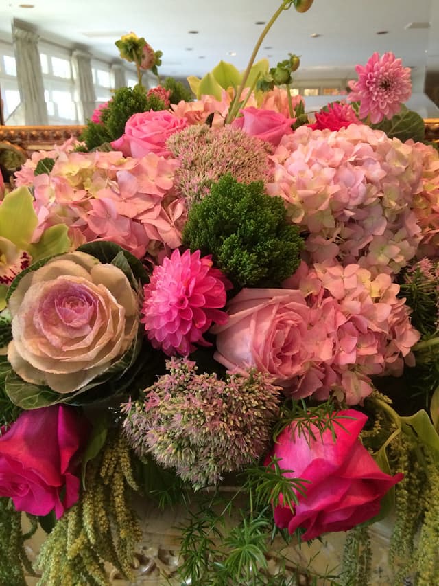 Low mounded centerpiece of pink dahlias, flowering kale, and hydrangea