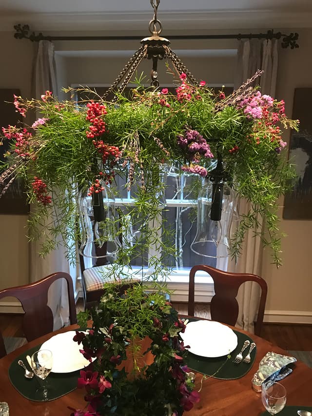 Suspended floral chandelier of greenery and blooms above a dining table