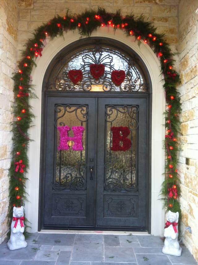 Front doors with evergreen garland and fresh carnation letter initials