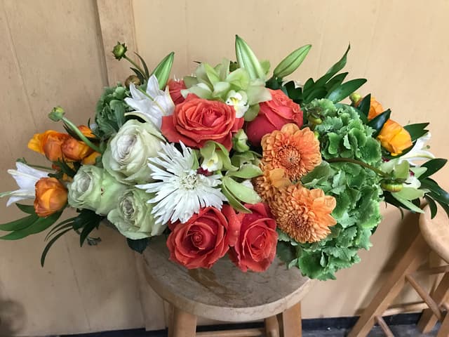 Fresh centerpiece of coral roses and green hydrangea