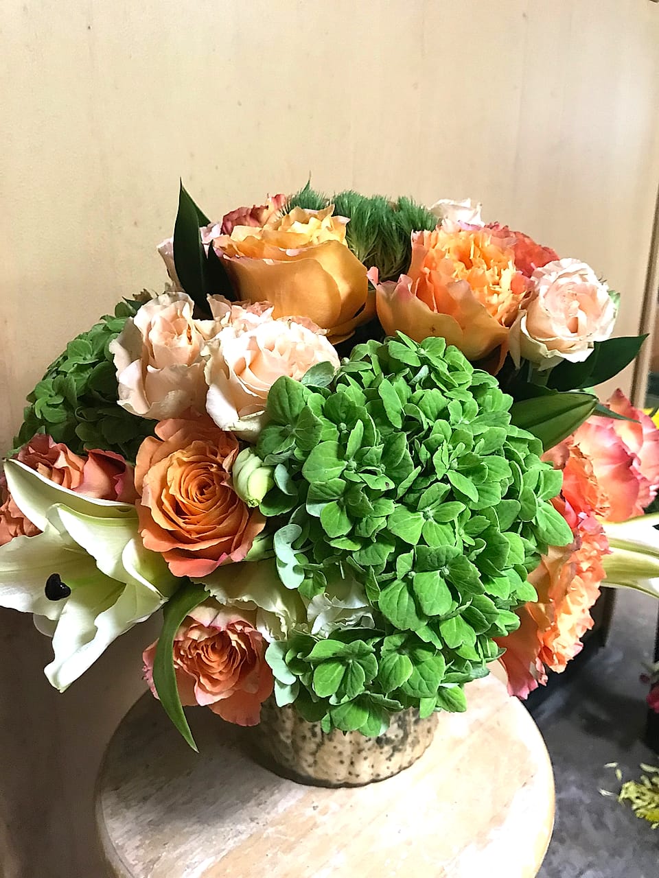 European-style garden arrangement with peach roses, lilies, and green hydrangea