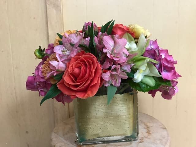 Compact pavé cube of roses, alstroemeria, and hydrangea in pinks and corals