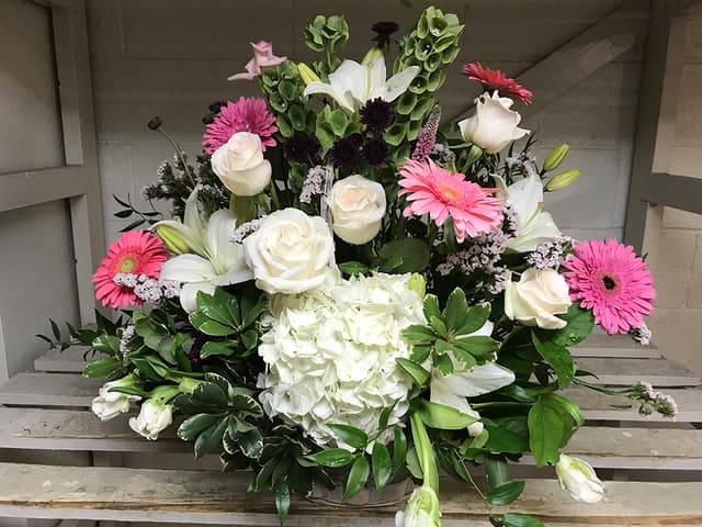Pink gerbera daisies, white roses, and hydrangeas in a garden-style arrangement