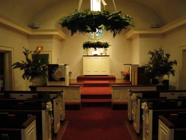 Ceremony aisle with hanging evergreen wreaths above the altar