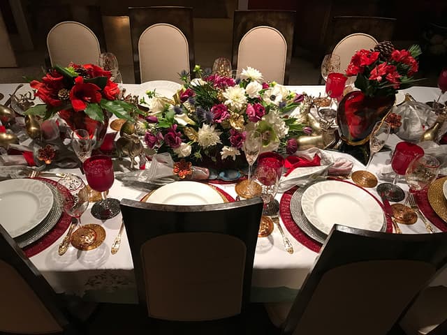 Formal holiday dinner table with red and white floral centerpieces