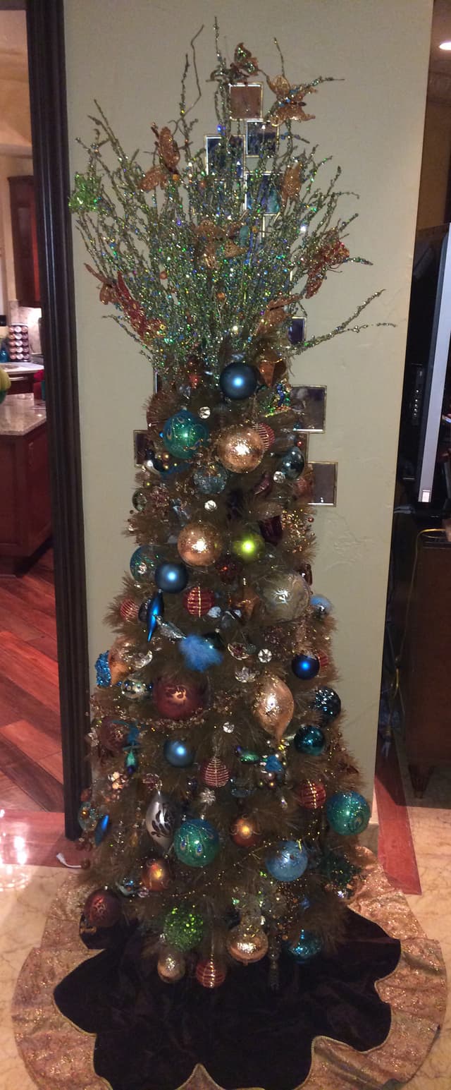 Slim pencil Christmas tree decorated with jewel-tone ornaments