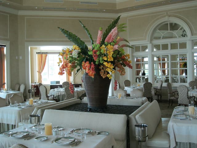 Large tropical arrangement in a dining room with orchids and ginger
