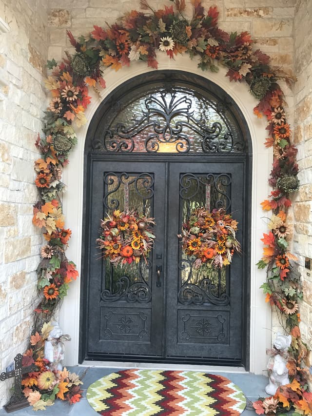 Front entry decorated with an arched fall garland and door wreaths