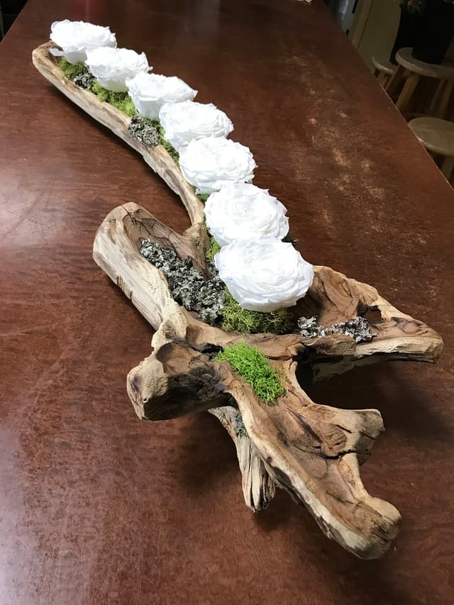 White preserved roses designed along a piece of natural driftwood