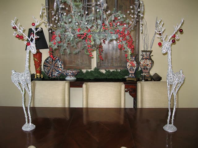 Christmas mantel display with a reindeer figure, red berries, and evergreens