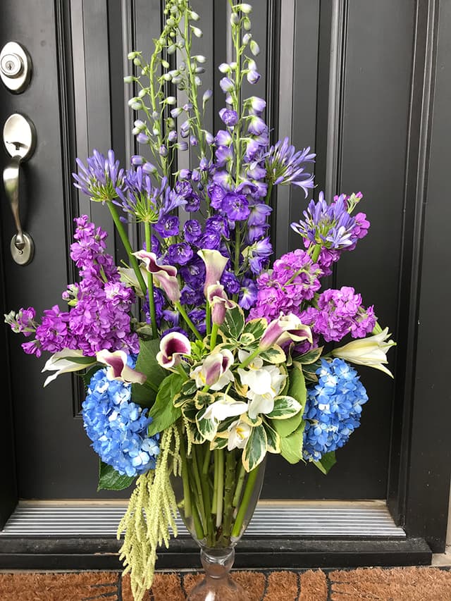 Front-door arrangement in shades of purple and blue with hydrangea and larkspur