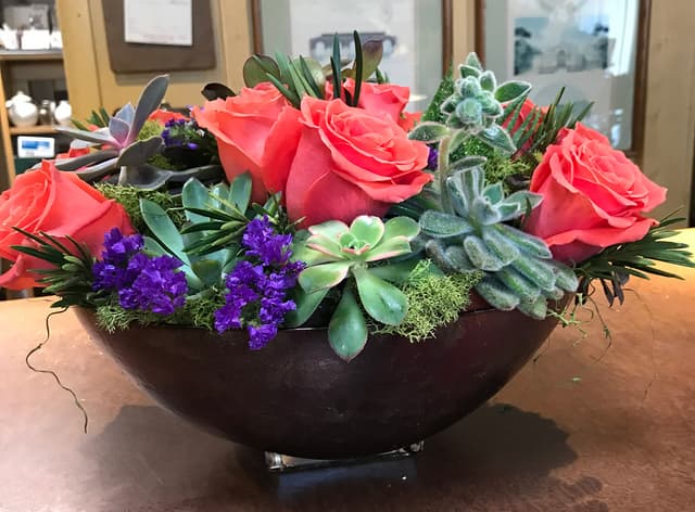 Modern pavé bowl of coral roses, succulents, and purple stock