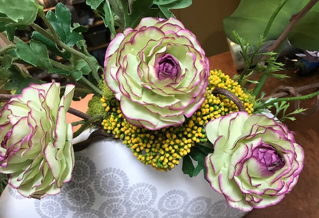 Close-up of variegated silk ranunculus blooms with yellow berry accents