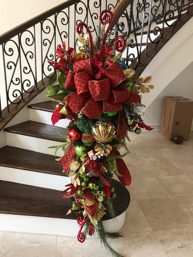 Whimsical red Christmas swag with ornaments cascading down a staircase