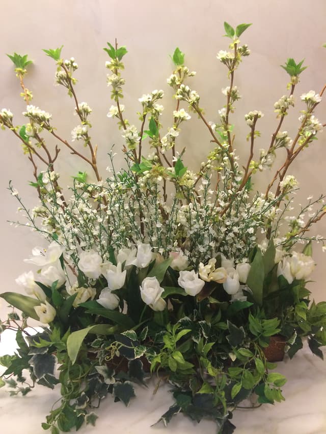 Tall white blooming branches with roses and ivy in a garden container